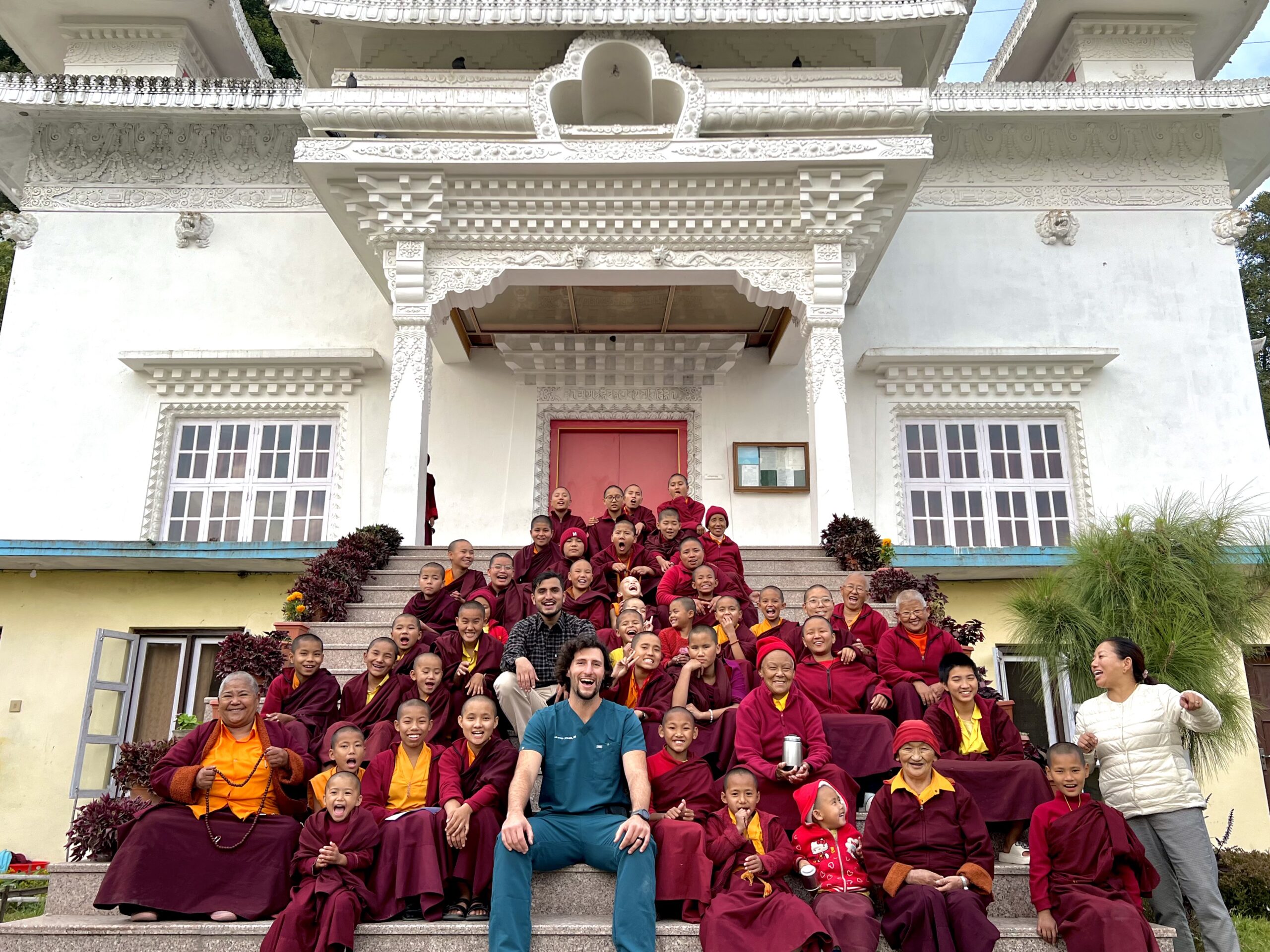 a large group of monk children sitting and laughing in front of a temple